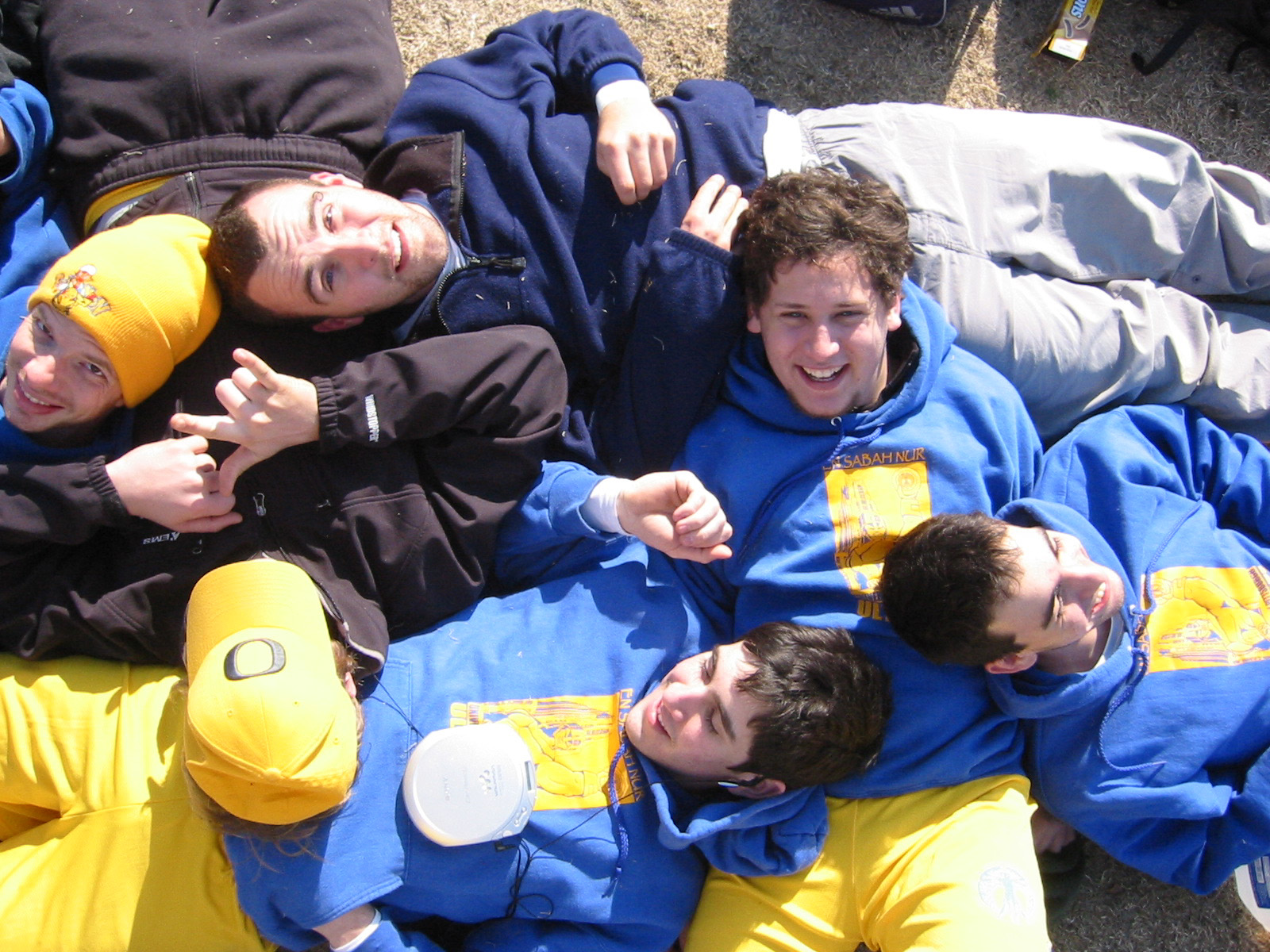 Pitt players in blue and gold hoodies lying together on the grass during the Clemson bye week, a disc resting among them